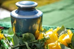 Close-up of a burial urn with yellow roses in the background.